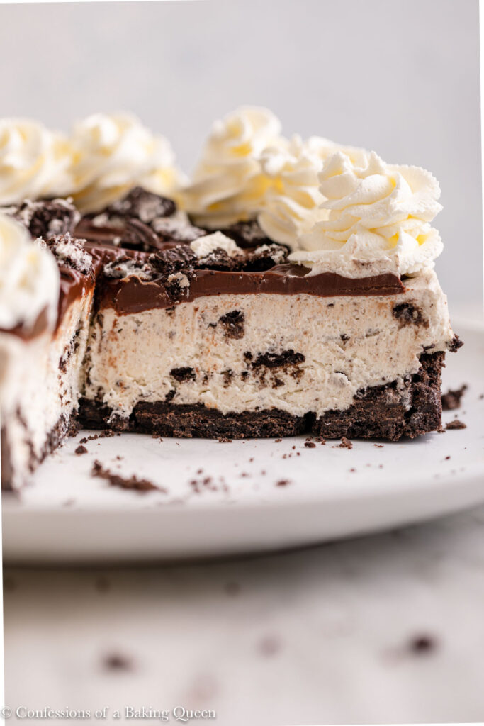 no bake oreo cheesecake cut with some slices removed on a white plate on a white marble surface