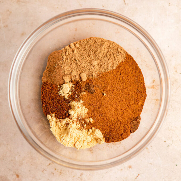 pumpkin pie spices in a glass bowl on a light brown surface