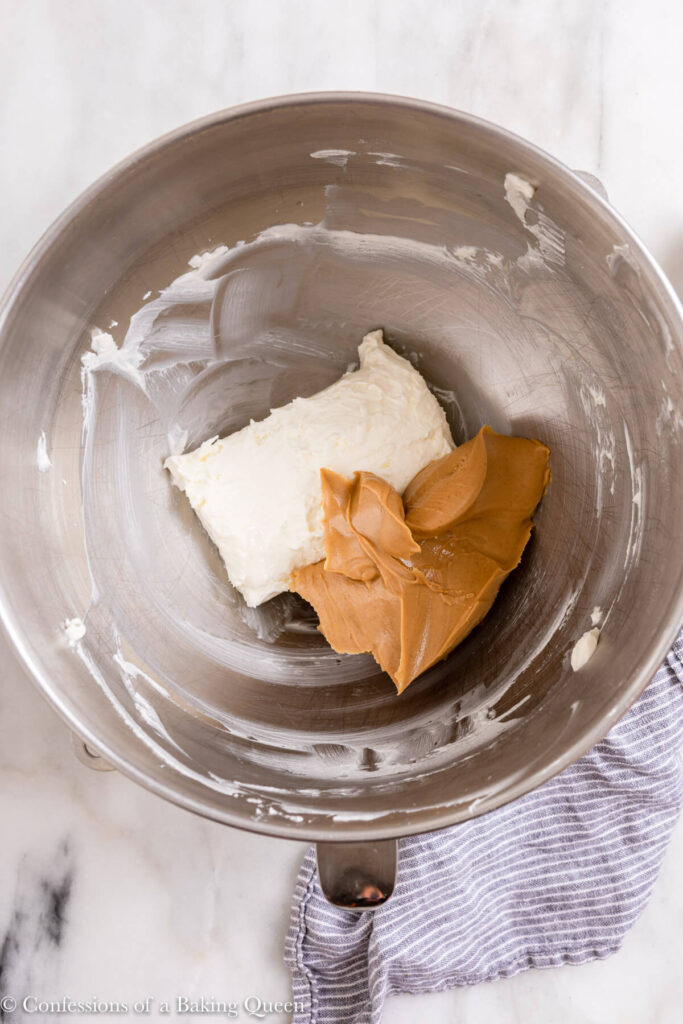peanut butter and cream cheese in a metal bowl on a white marble surface with a blue linen