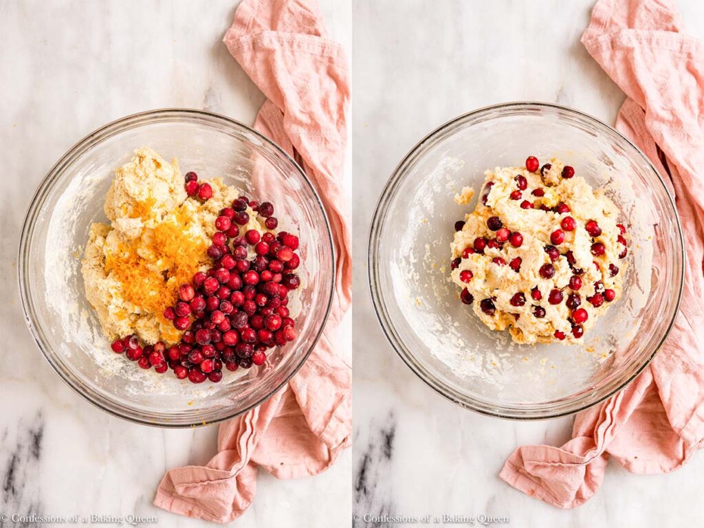 cranberries and orange zest added to scone batter in a glass bowl on a white marble surface with a pink linen