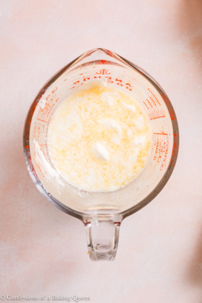 orange juice, buttermilk and sour cream in a glass measuring cup on a light pink surface