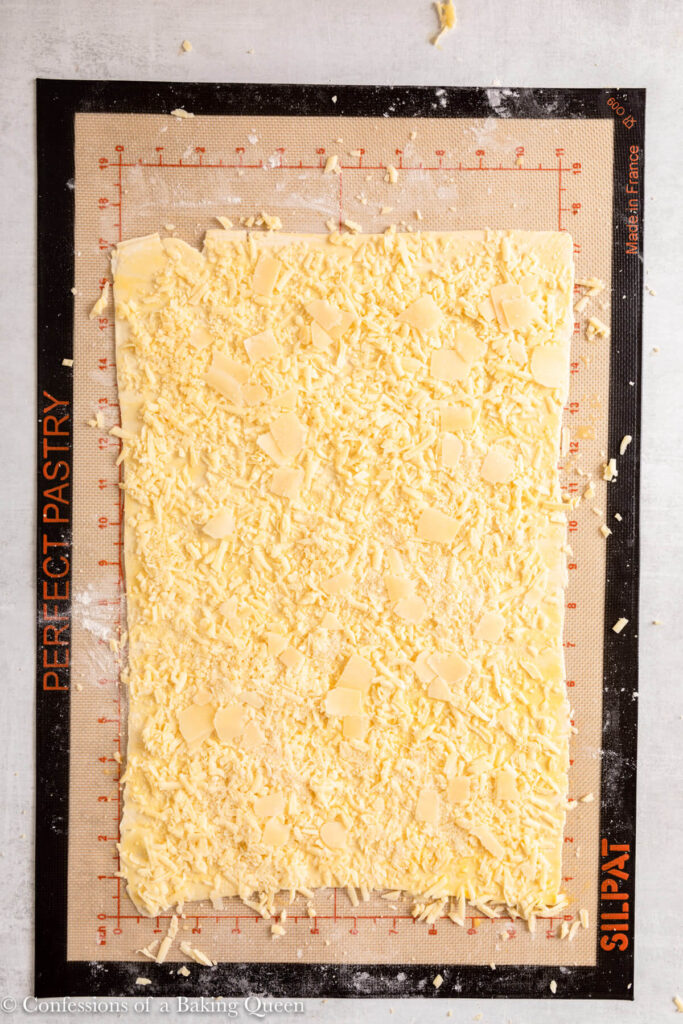 cheddar cheese and parmsean cheese sprinkled on top of pastry on a light grey surface