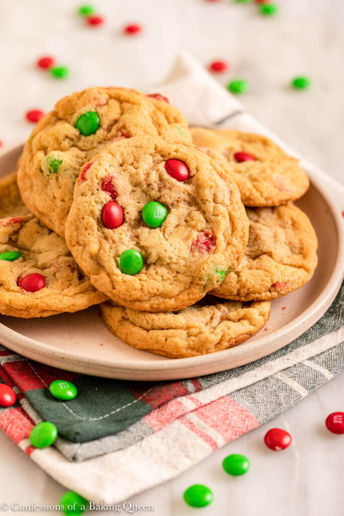 red and green M&m cookies on a light pink plate on top of a christmas linen