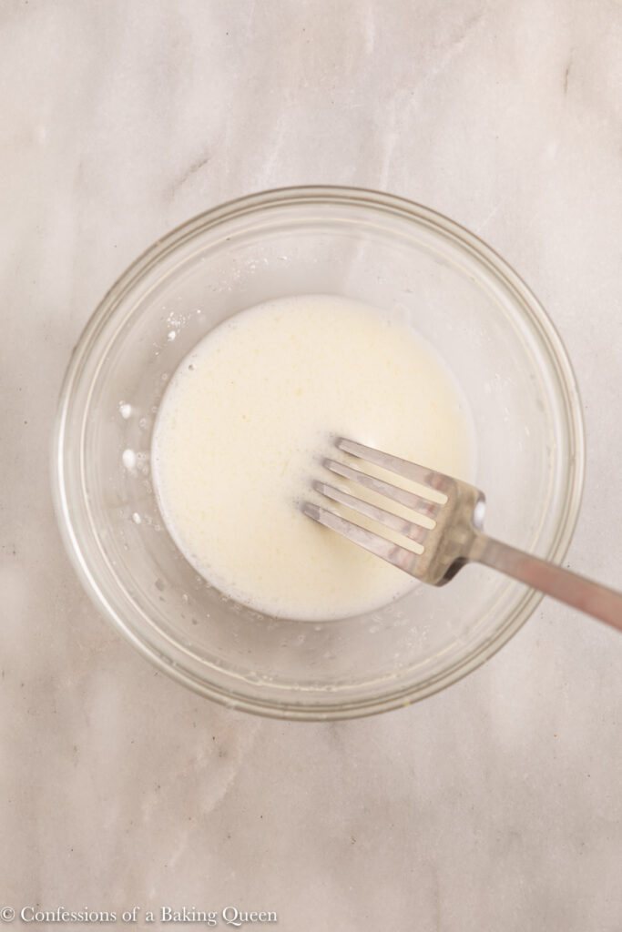 lemon juice and cornstarch mixed together with a fork in a glass bowl on a white marble surface