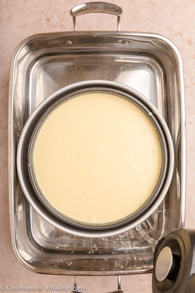 mascarpone cheesecake baking in a water bath on a light brown surface