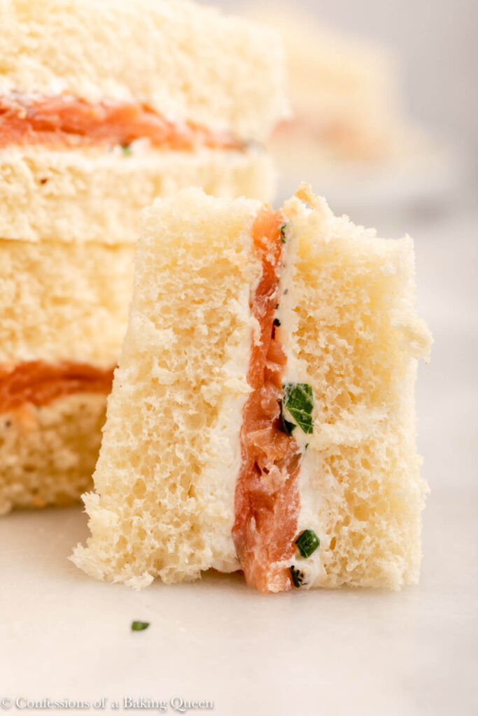 close up of a cream cheese and salmon sandwich on a white marble surface