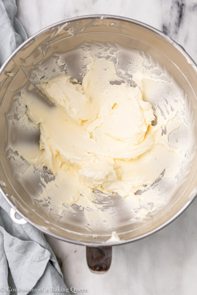 butter and mascarpone whipped together until light and fluffy in a metal mixing bowl on a white marble surface with a light blue linen