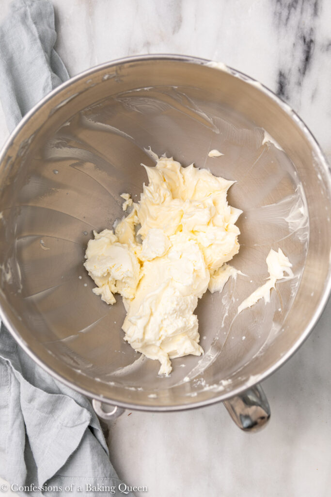 whipped butter and softened mascarpone in a metal bowl on a white marble surface with a light blue linen
