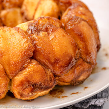 up close of cream chesse monkey bread on a white platter on top of a blue linen