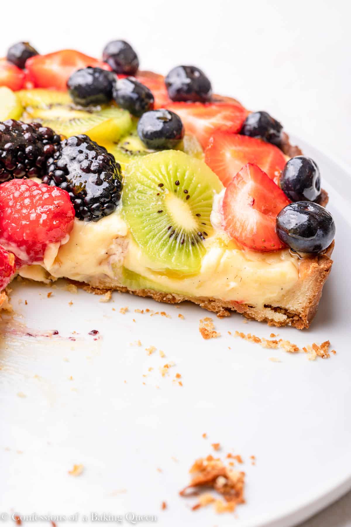 cut open french fresh fruit tart on a white plate on a light surface