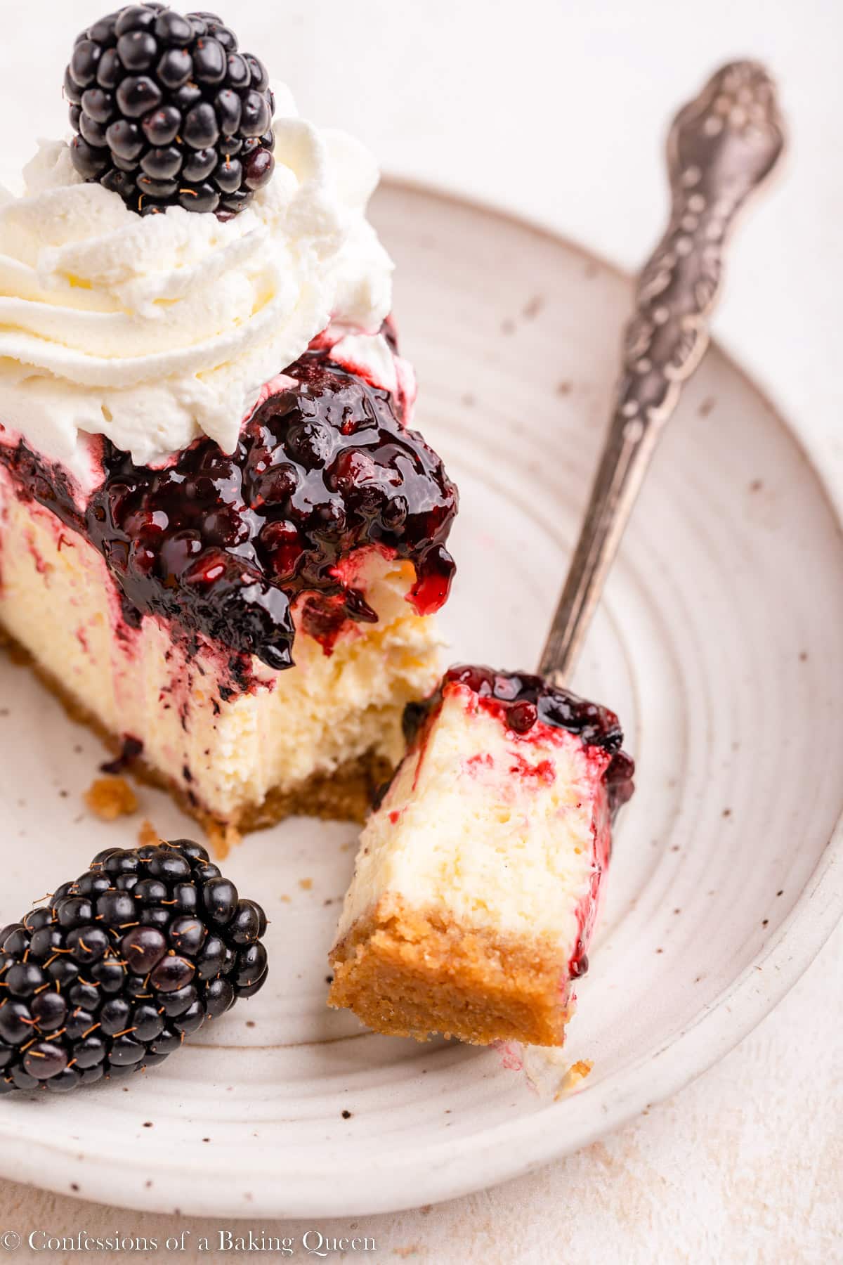 up close of a fork taking a bite of blackberry cheesecake