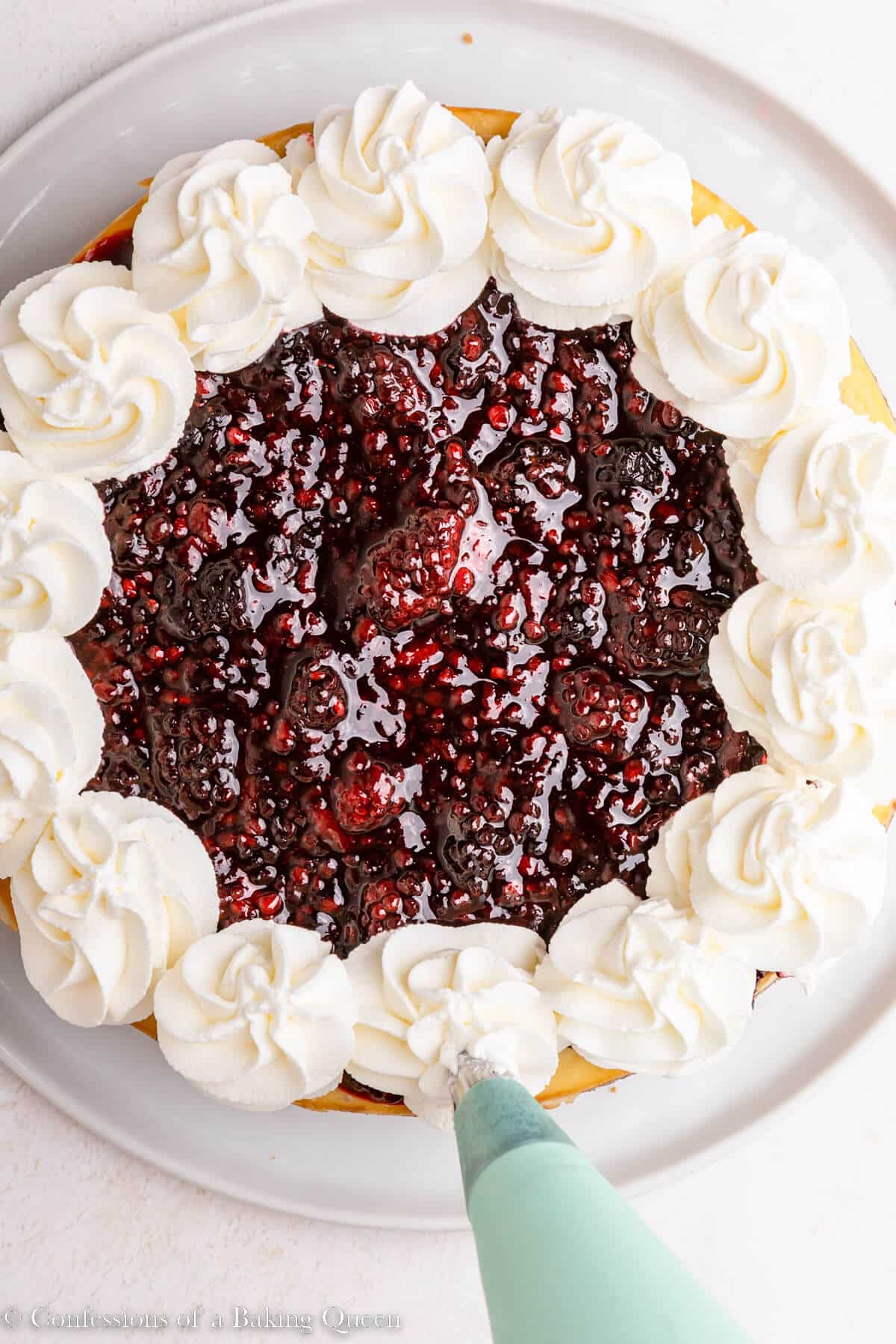whipped cream piped on top of blackberry cheesecake on a light surface