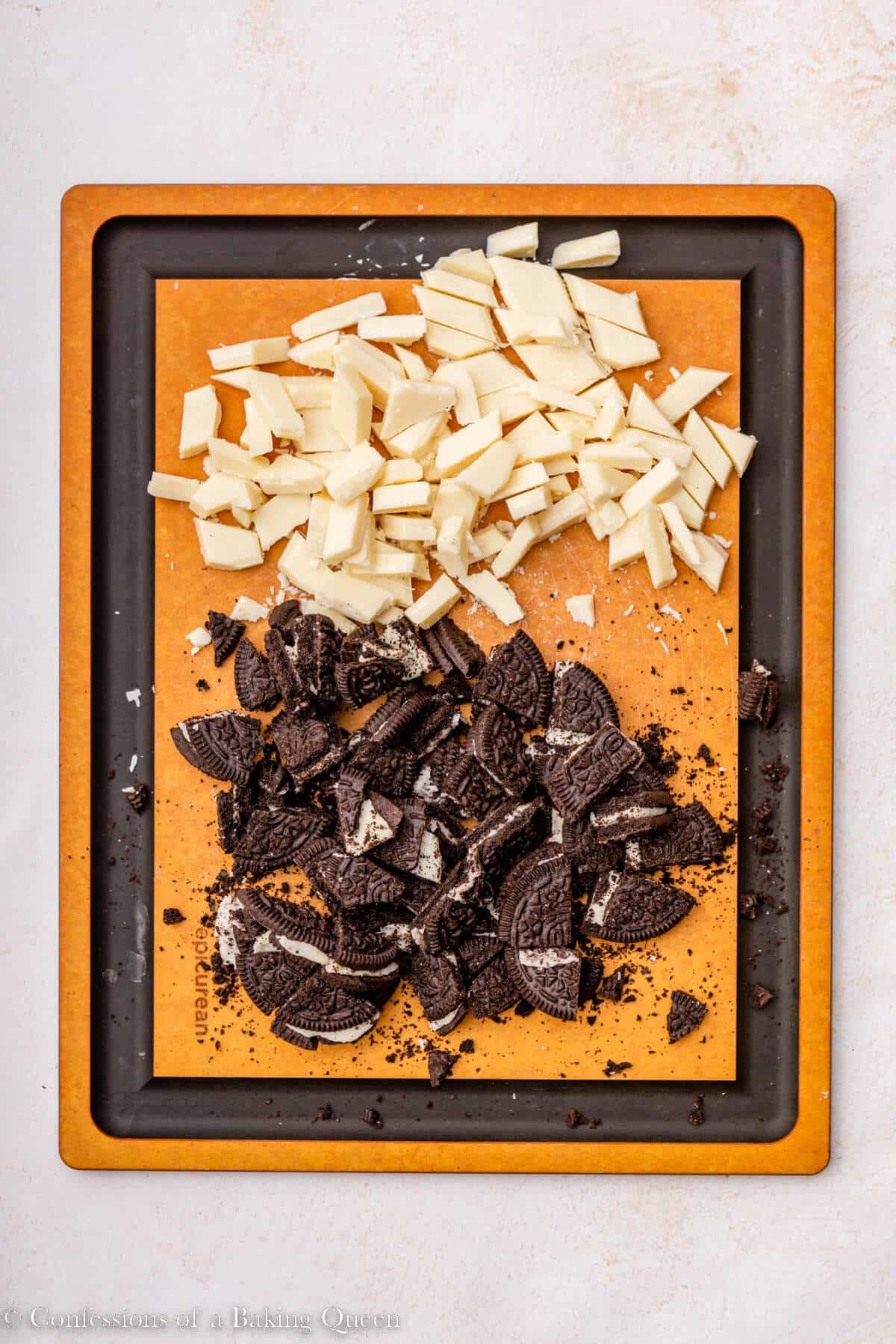 white chocolate and oreos cut into chunks on a small wood cutting board on a light surface