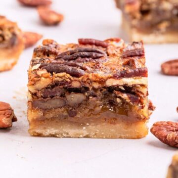 pecan pie bars laid out on a light pink surface