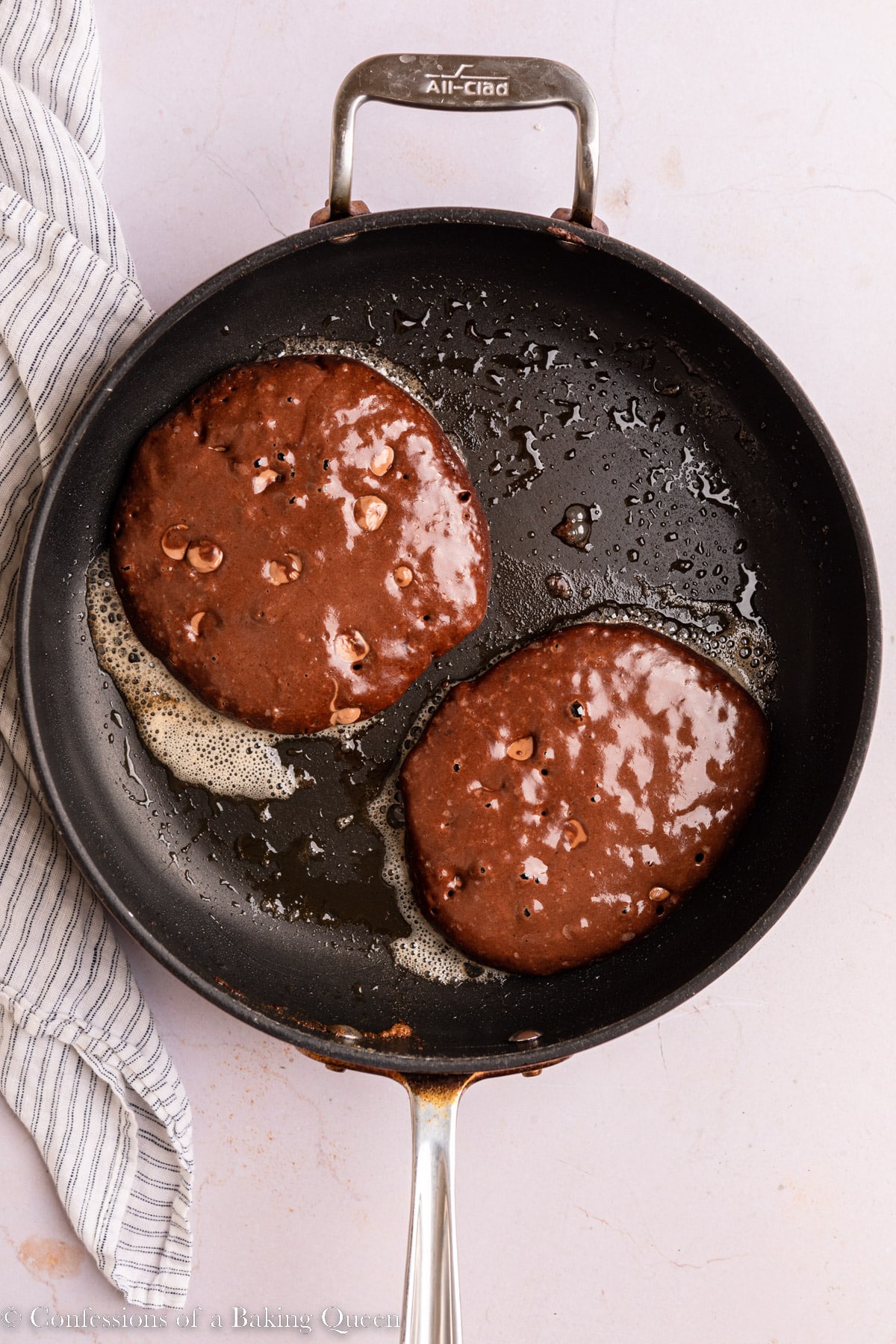 Chocolate pancakes cooking in a skillet.