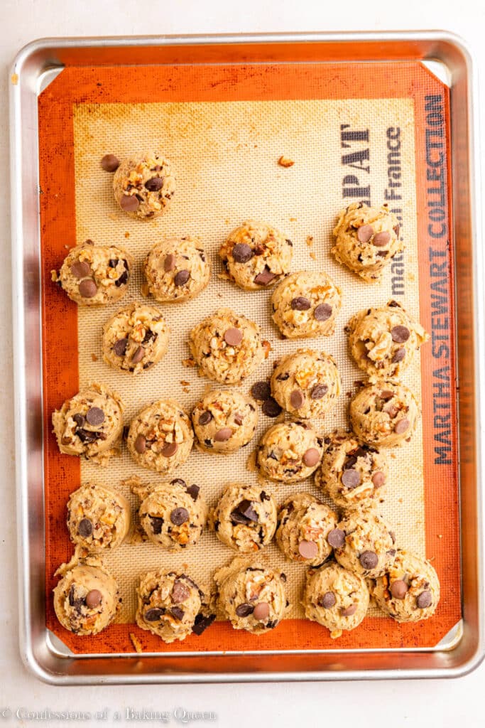 chocolate chip walnut cookie dough balls on a silpat lined baking sheet