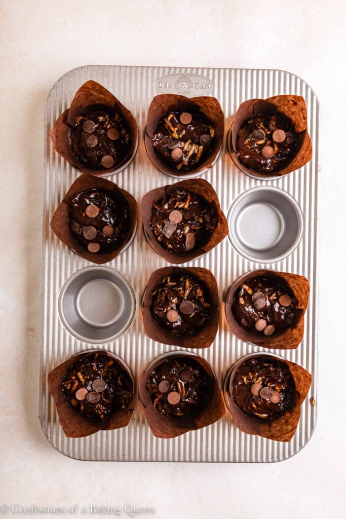 chocolate chips added to the top of chocolate zucchini muffins before baking in a metal pan