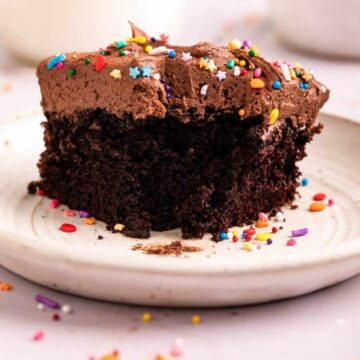 slice of chocolate cake with a bite taken out on a light surface with sprinkles scattered