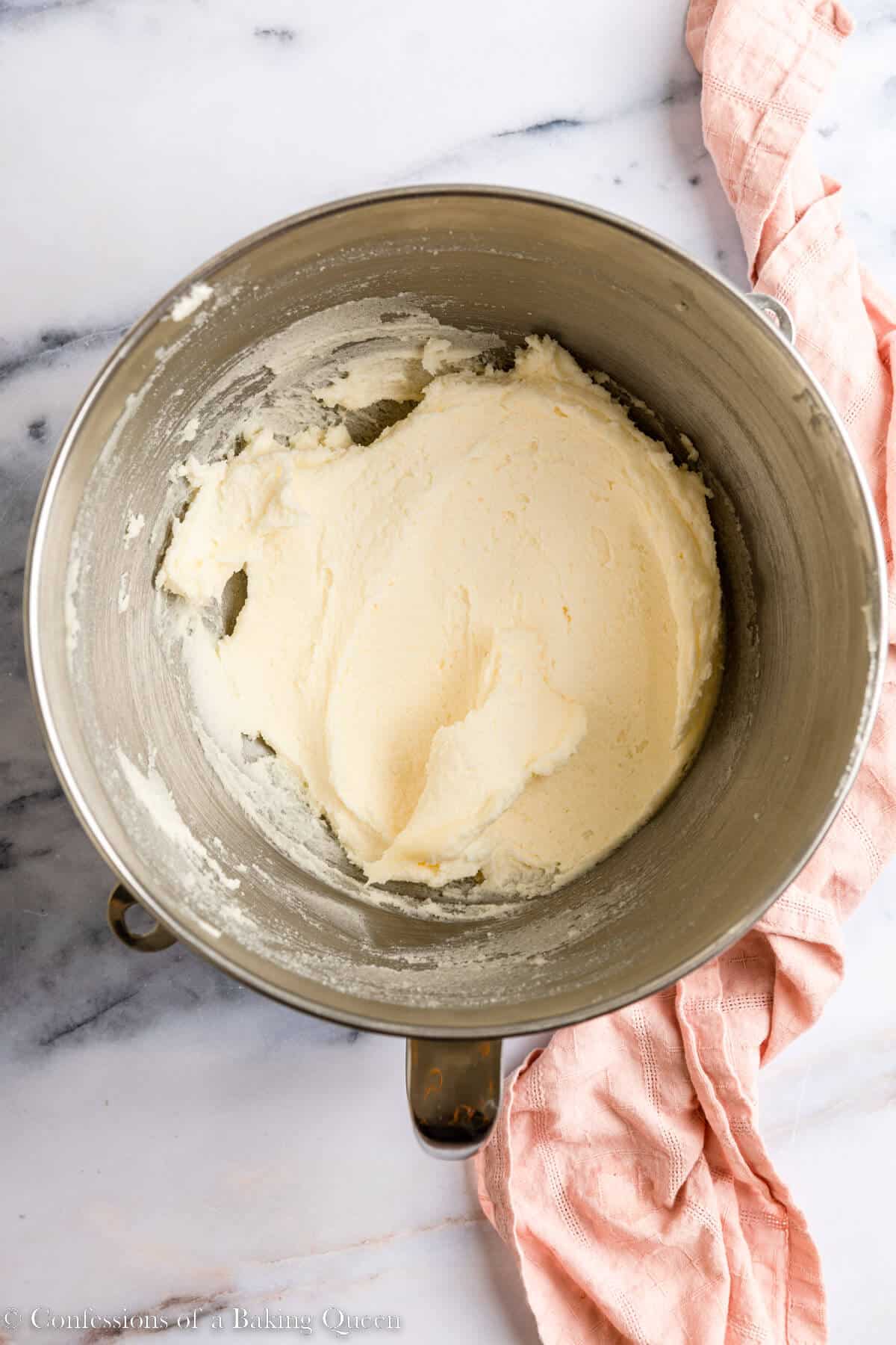 butter and sugar creamed together until light and fluffy in a metal bowl on a light white marble surface with a pink linen