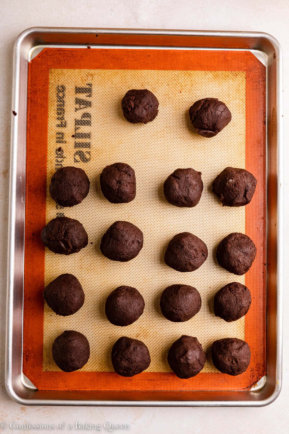 chocolate marshmallow cookie dough balls on a silpat lined baking sheet on a light surface