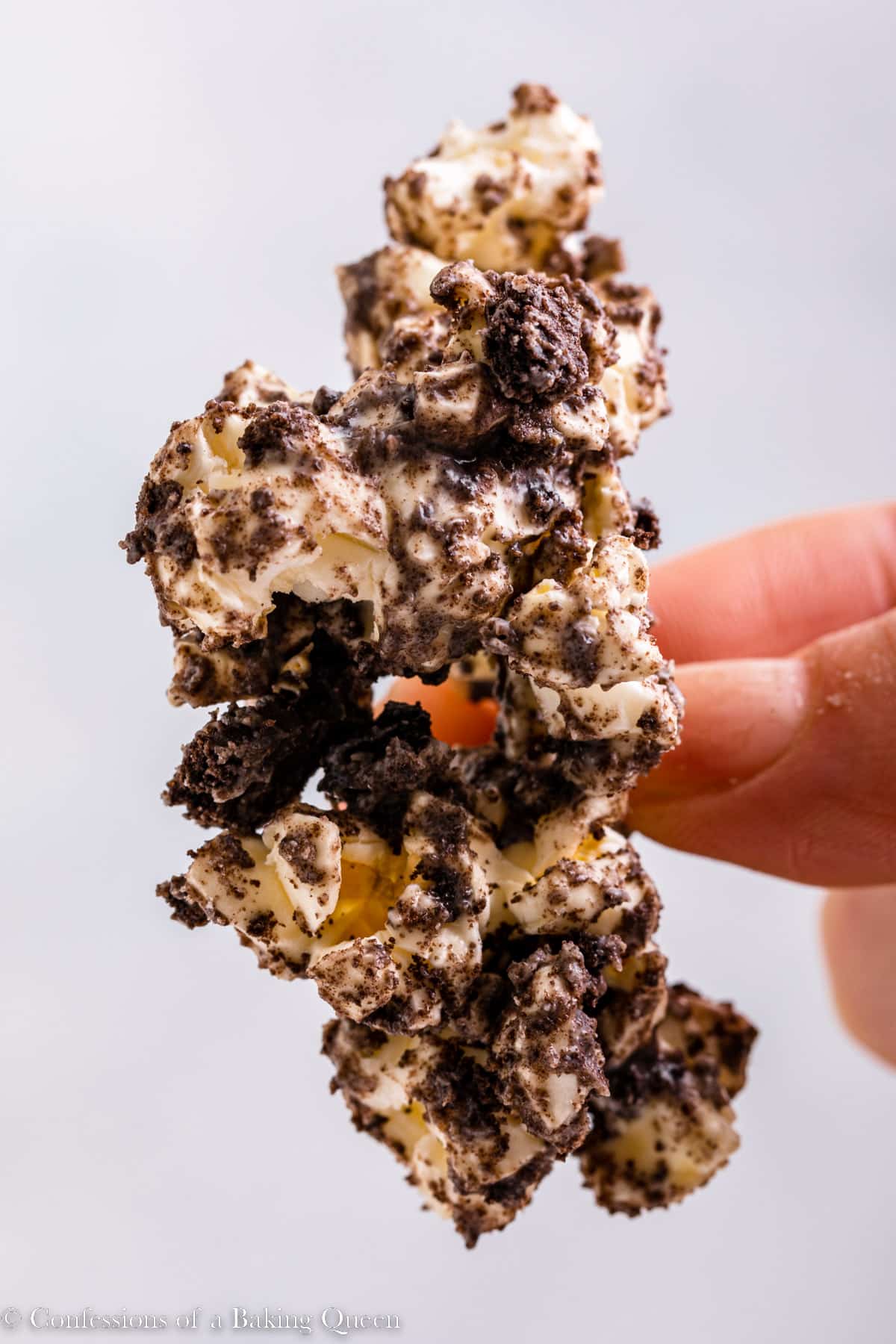 hand holding a chunk of oreo white chocolate popcorn up to the camera