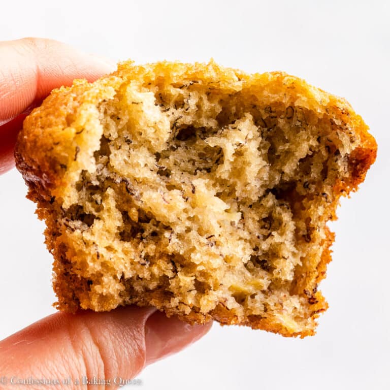 A hand holding a banana bread muffin with a bite taken out of it.