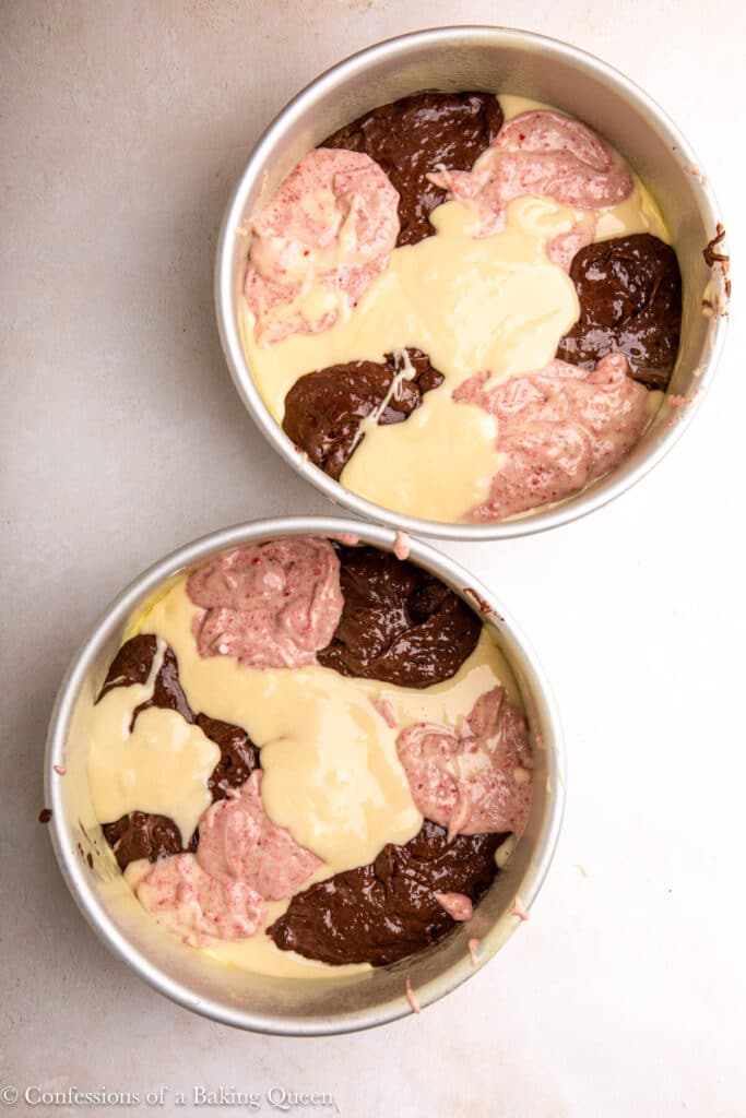 Neapolitan cake batter in caked pans on a light surface