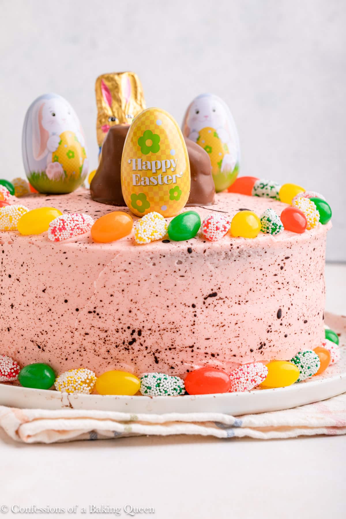 easter cake decorated with sees candies on a white plate on top of a checkered linen on a light surface