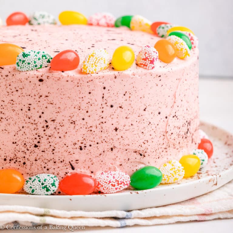 easter cake decorated with jelly beans on a white plate on a light surface with a checkered linen