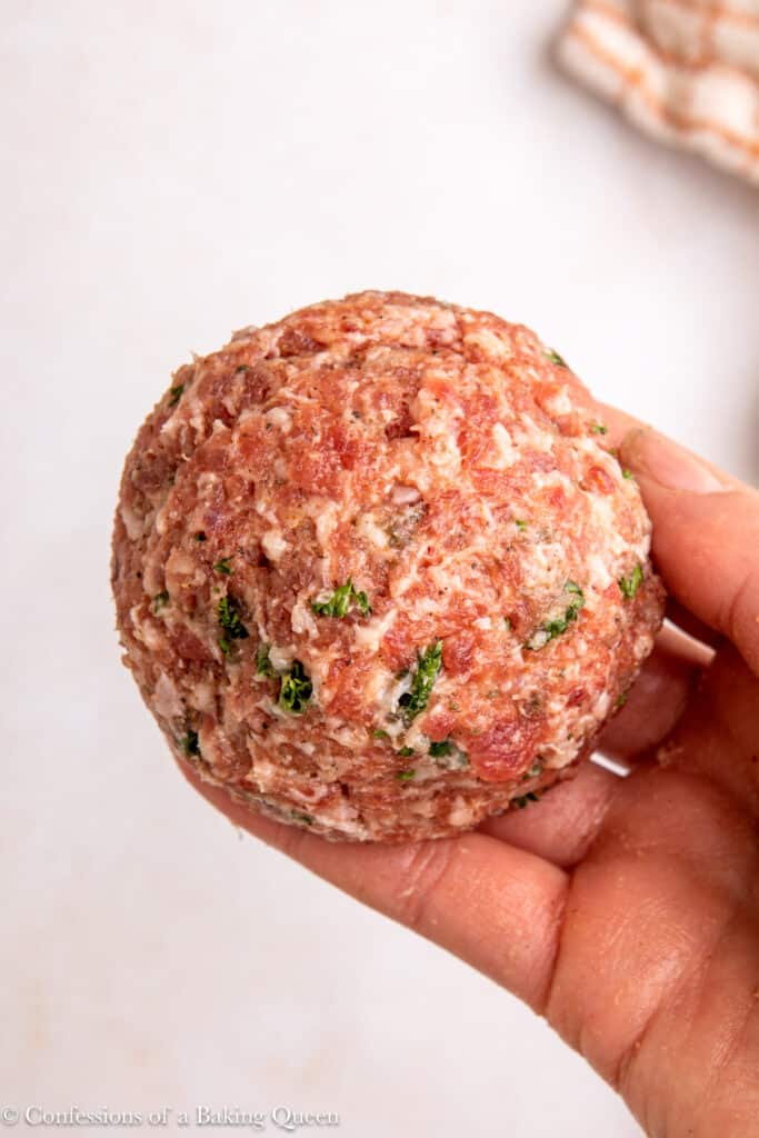 boiled egg rolled into sausage meat into a ball held up to the camera