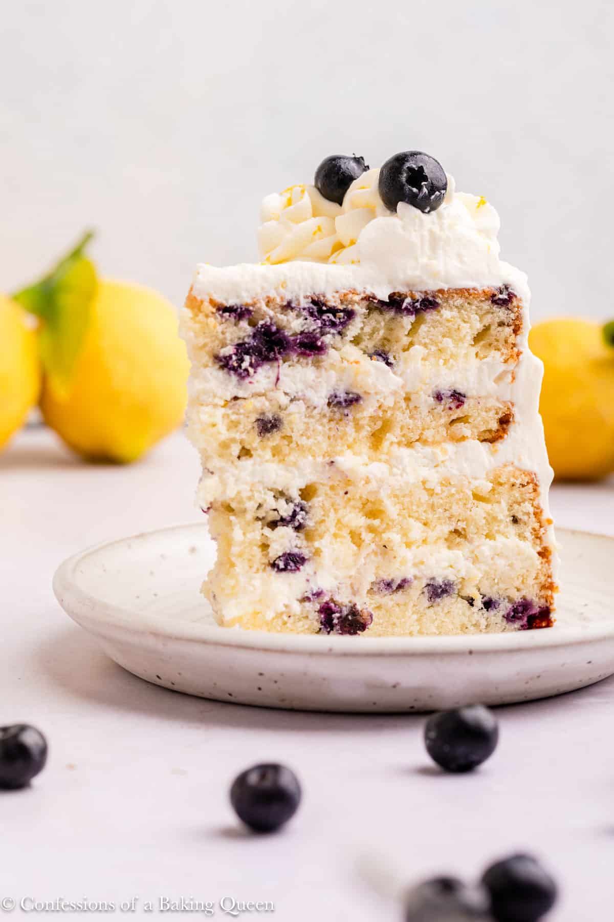 slice of lemon blueberry cream cake on a white plate on a light surface