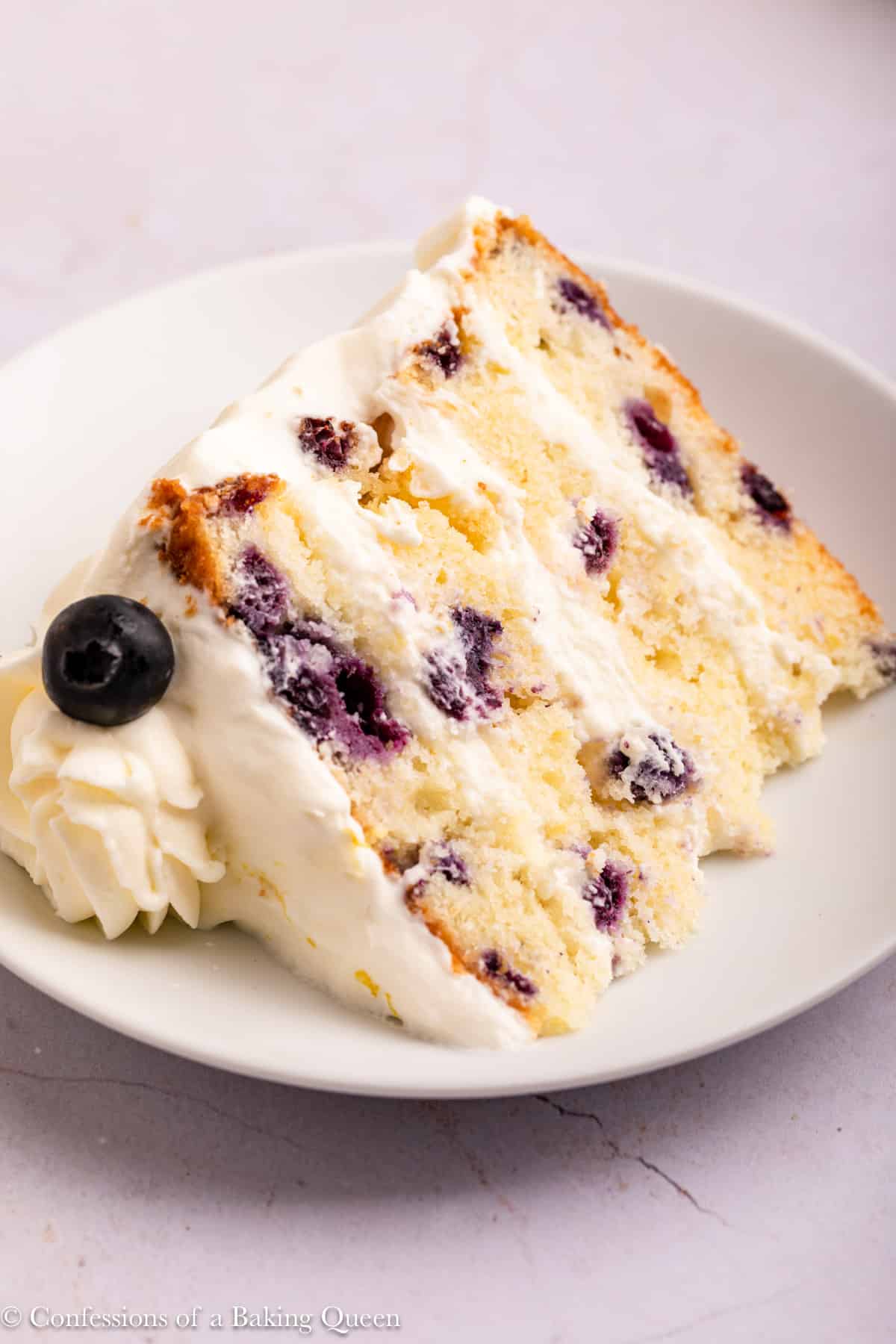 slice of blueberry lemon cake on a white plate on a light surface