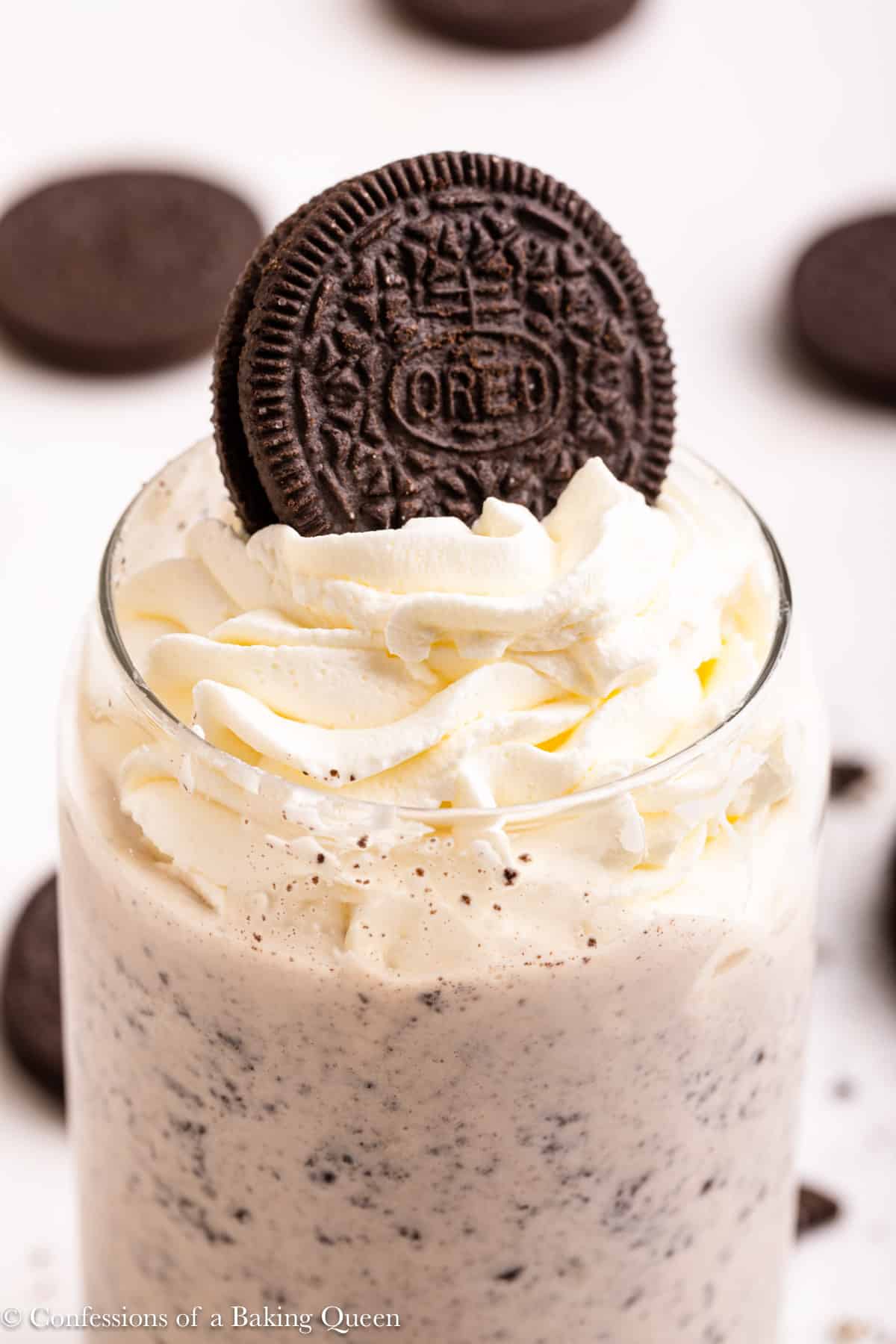 Closeup of an Oreo milkshake topped with whipped cream and an Oreo.
