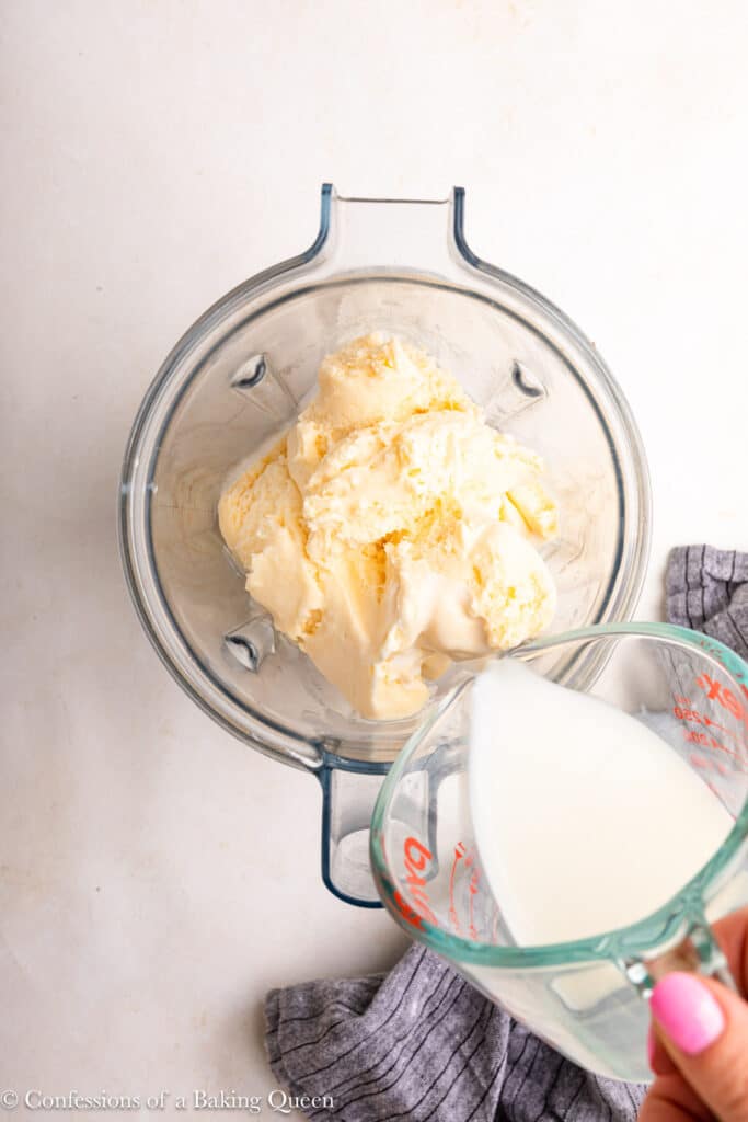 Adding milk to vanilla ice cream in a blender.