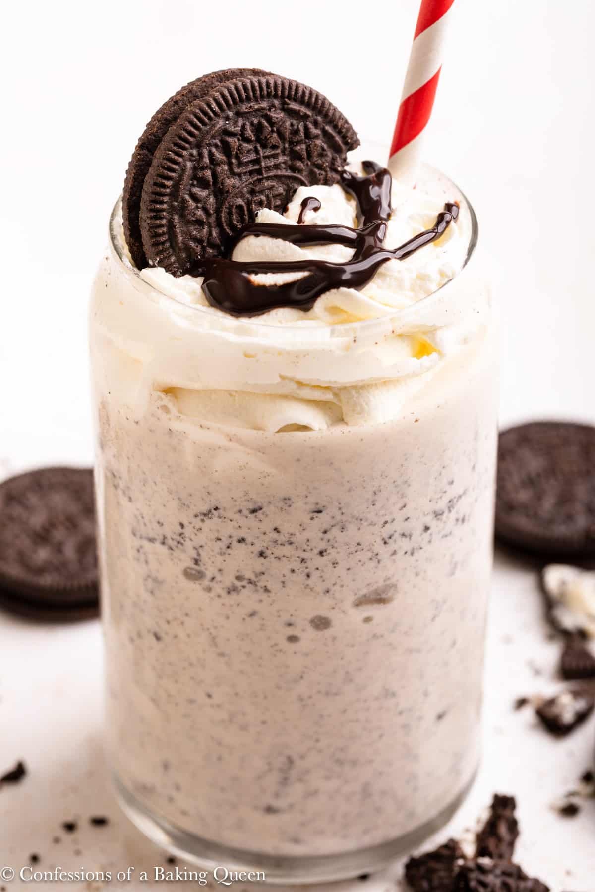An Oreo Milkshake with a straw topped with whipped cream, chocolate sauce, and an Oreo.
