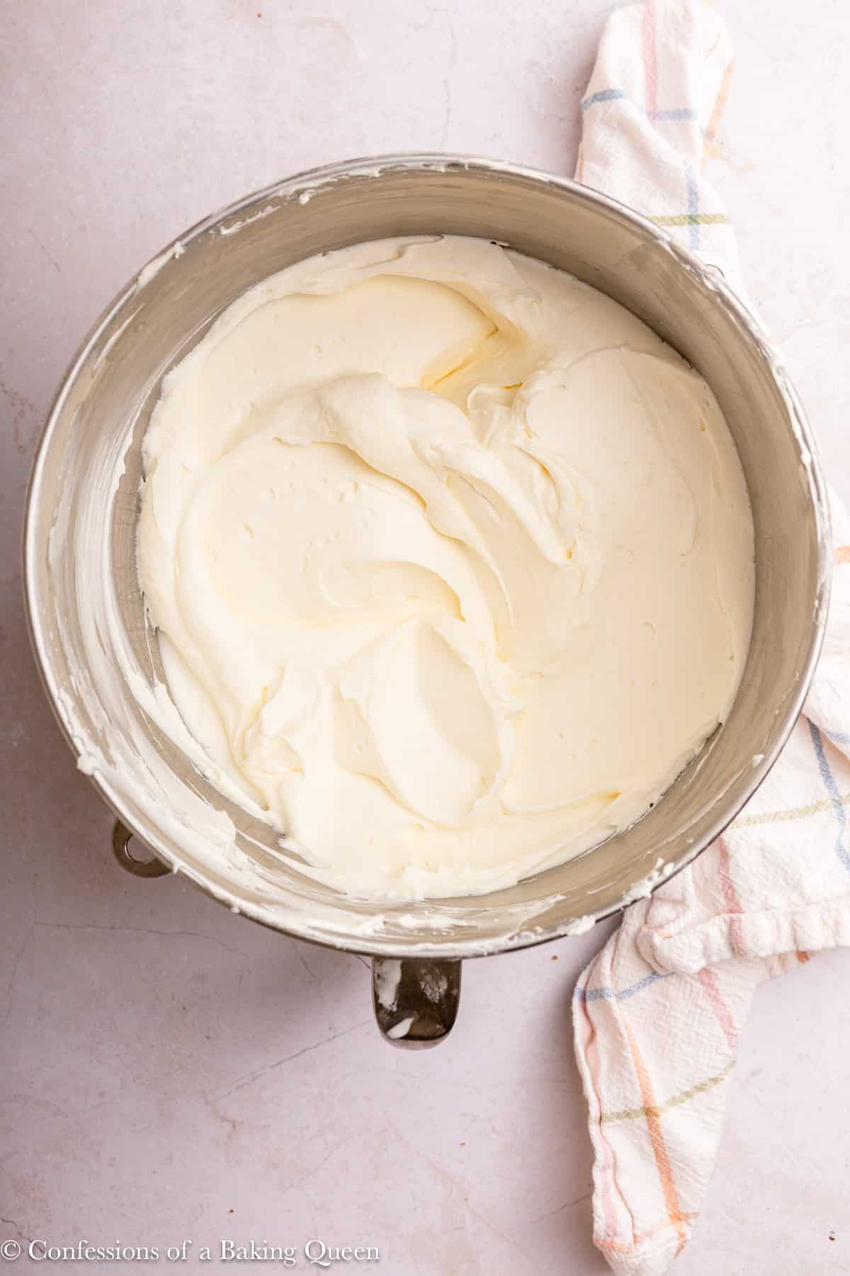 bowl of lemon whipped cream cream cheese frosting on a light surface with a colorful linen