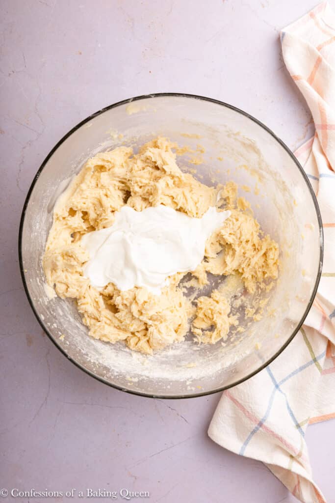 Adding Greek yogurt to creamed butter, sugar, and lemon zest.