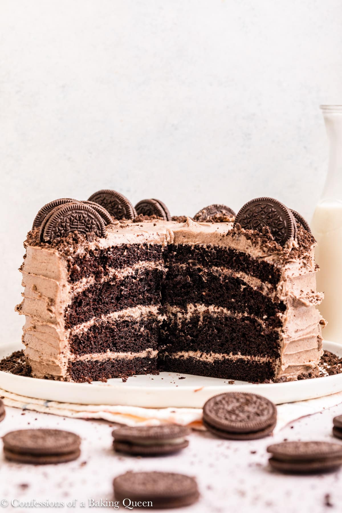 Oreo cake on a serving platter with a large slice or two taken out of it surrounded by Oreos.