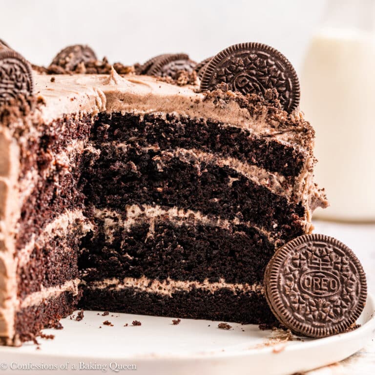 Oreo cake on a serving plate with a big slice taken out of it.