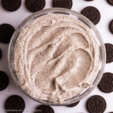 oreo frosting in a glass bowl next to oreos on a light surface