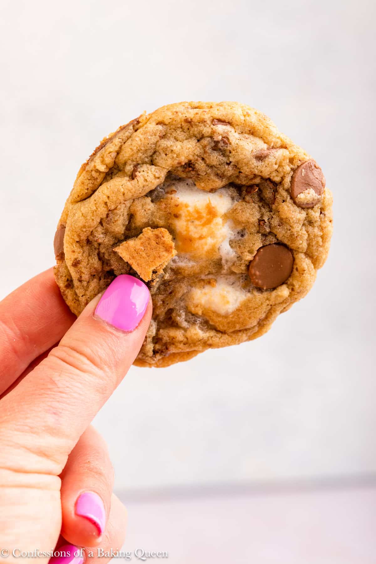 A hand holding a s'mores cookie.