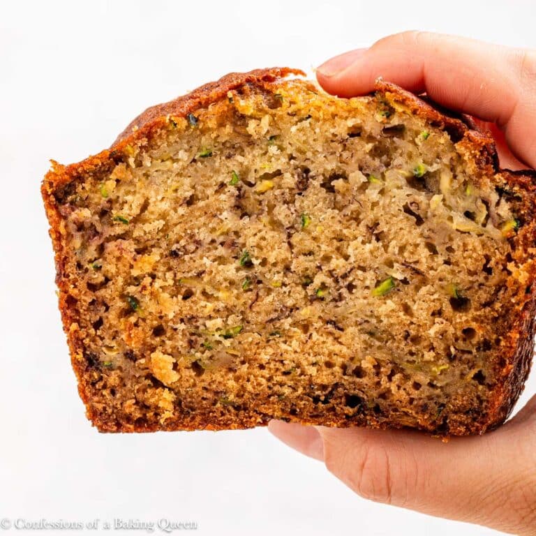 hand holding a slice of zucchini banana bread up to the camera.