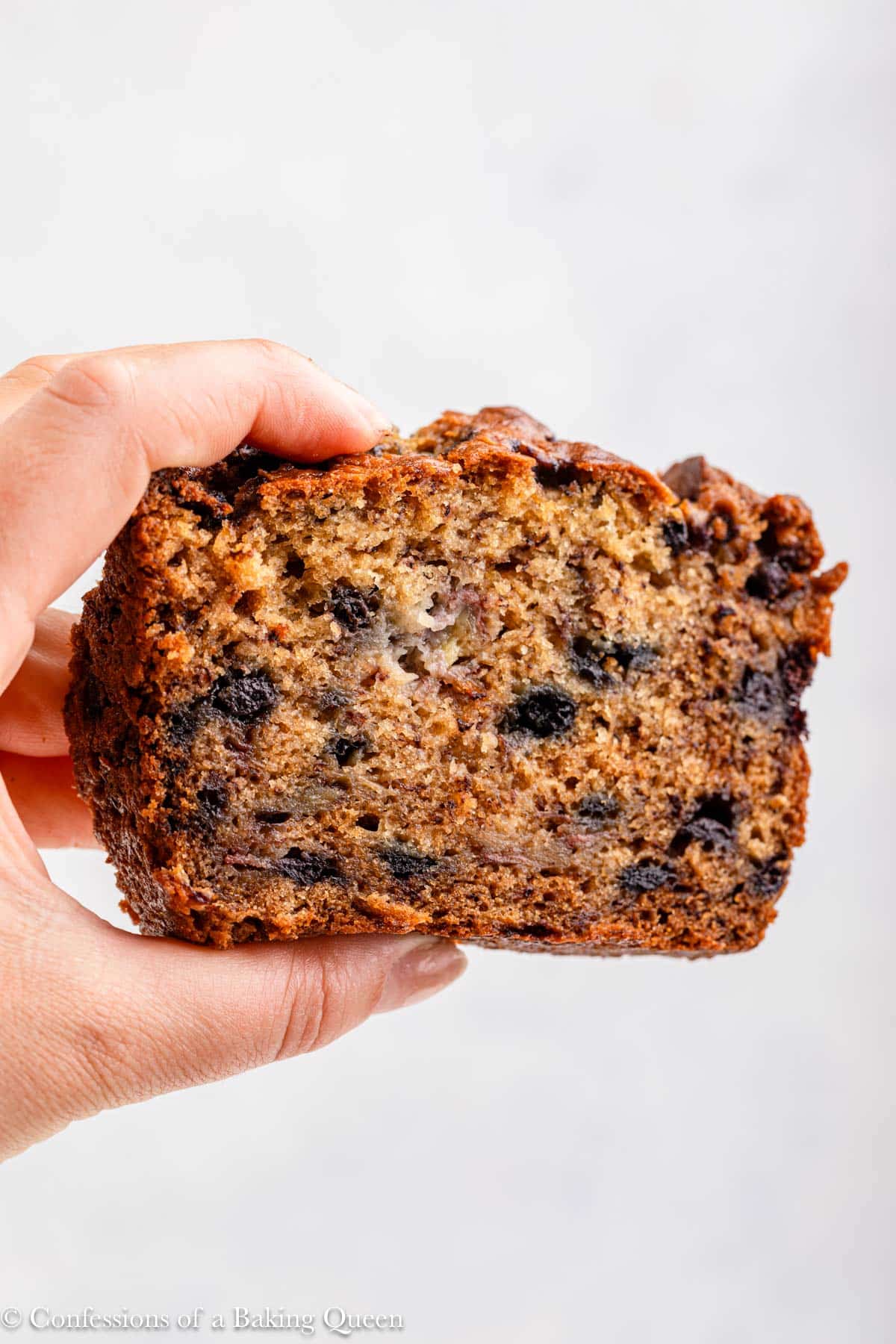 hand holding a slice of blueberry banana bread up to the camera.