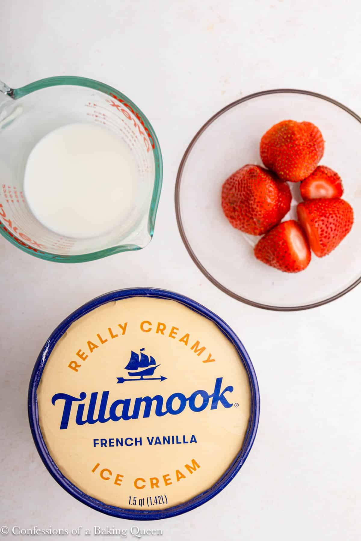 tillamook vanilla ice cream next to a bowl of strawberries and some milk on a light surface