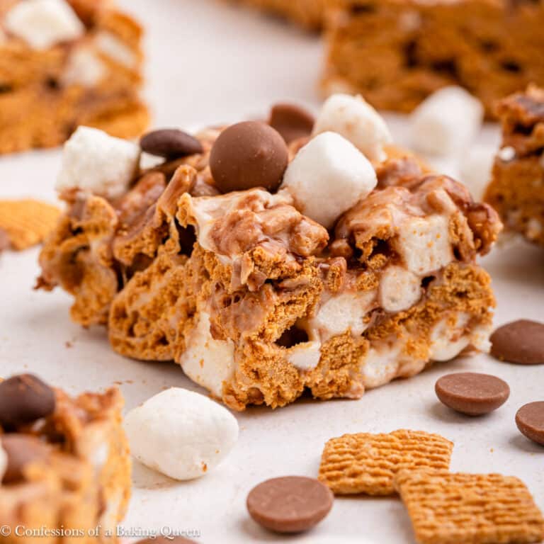 s'mores treats laid out on a light surface with marshmallows, chocolate chips and golden grahams.