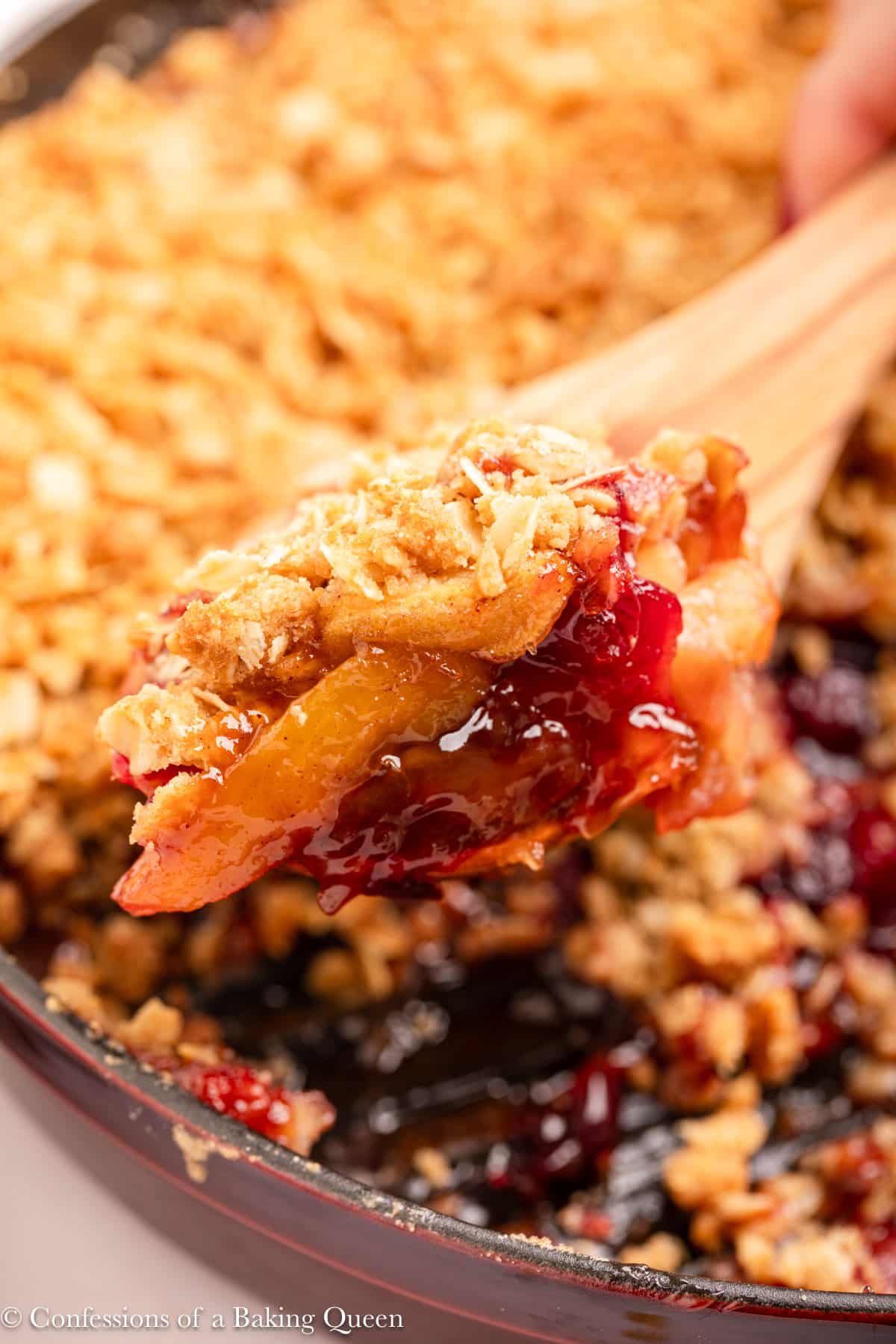 wooden spoon holding a spoonful of apple cranberry crisp.