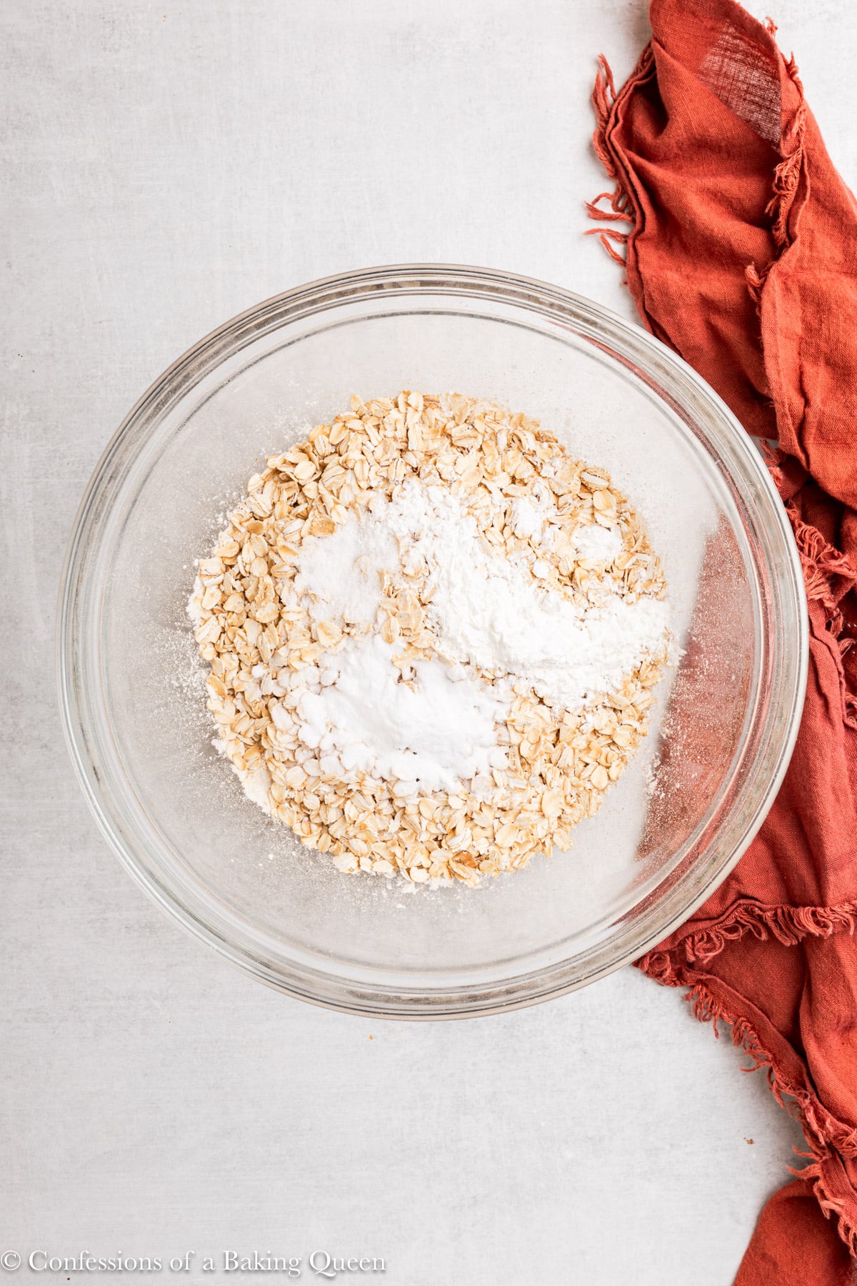 dry ingredients mixed together in a glass bowl on a grey surface with an orange linen.