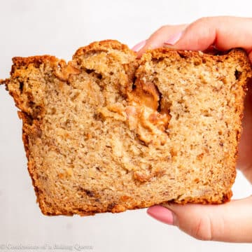 hand holding a slice of peanut butter banana bread up to the camera.