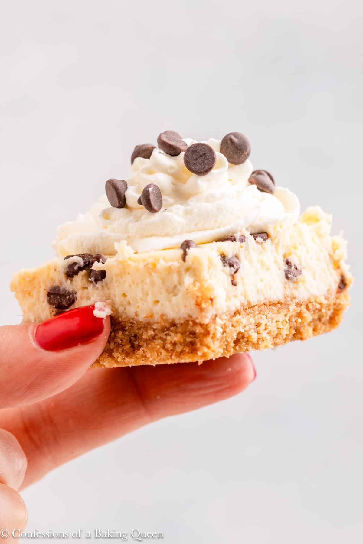 hand holding a chocolate chip cheesecake bar up to the camera.